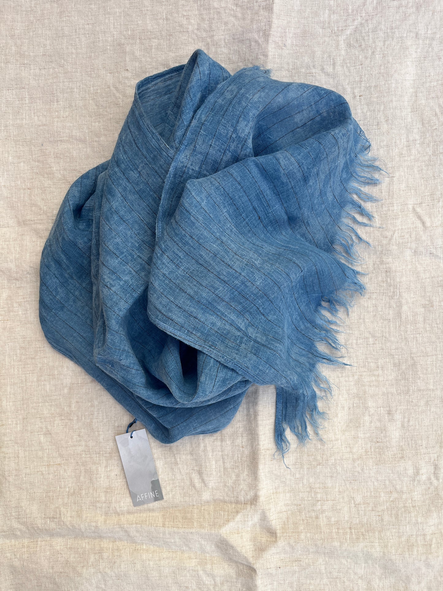 Indigo dyed blue scarf with black pinstripes on a table.