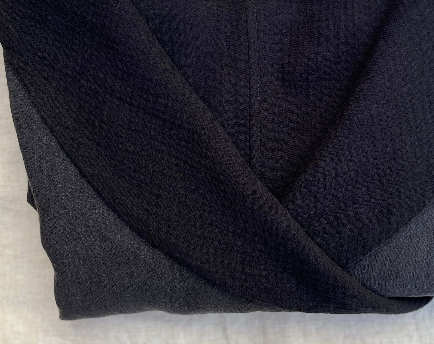 Close up photo of a folded black linen robe with an organic cotton double gauze lining.