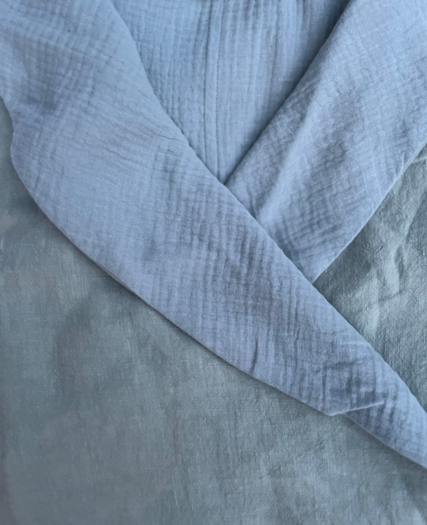 A close up image of a mint green colored linen robe with its soft organic cotton double gauze lining.