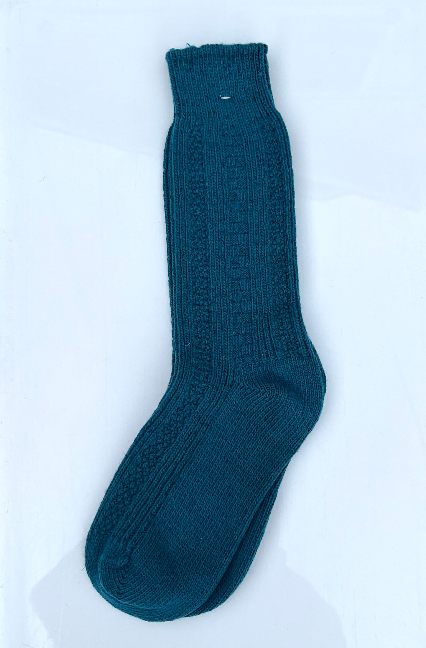 Dark turquoise blue color merino wool crew socks, laying flat.