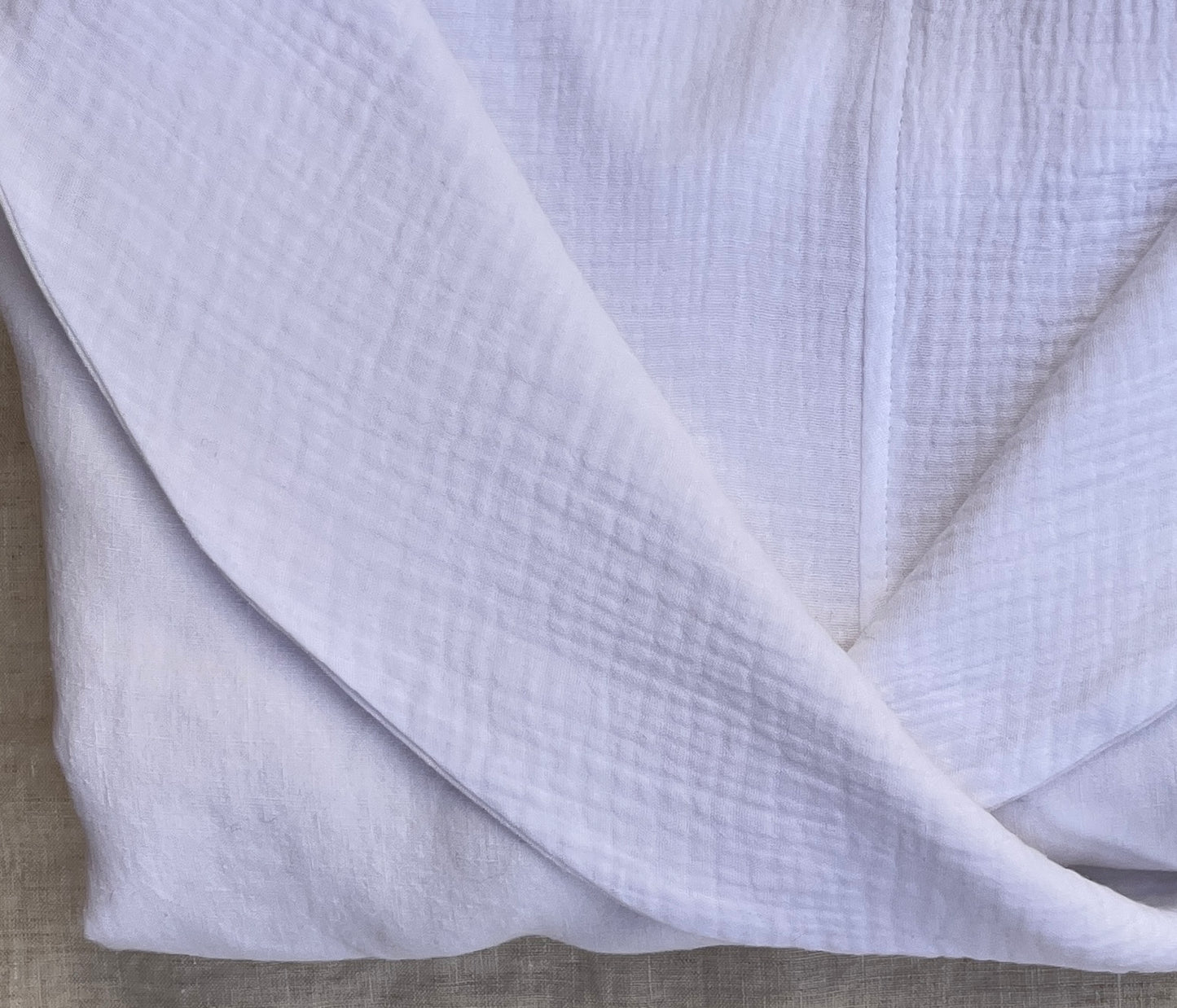 Close up photo of a folded white linen robe with an organic cotton double gauze lining.