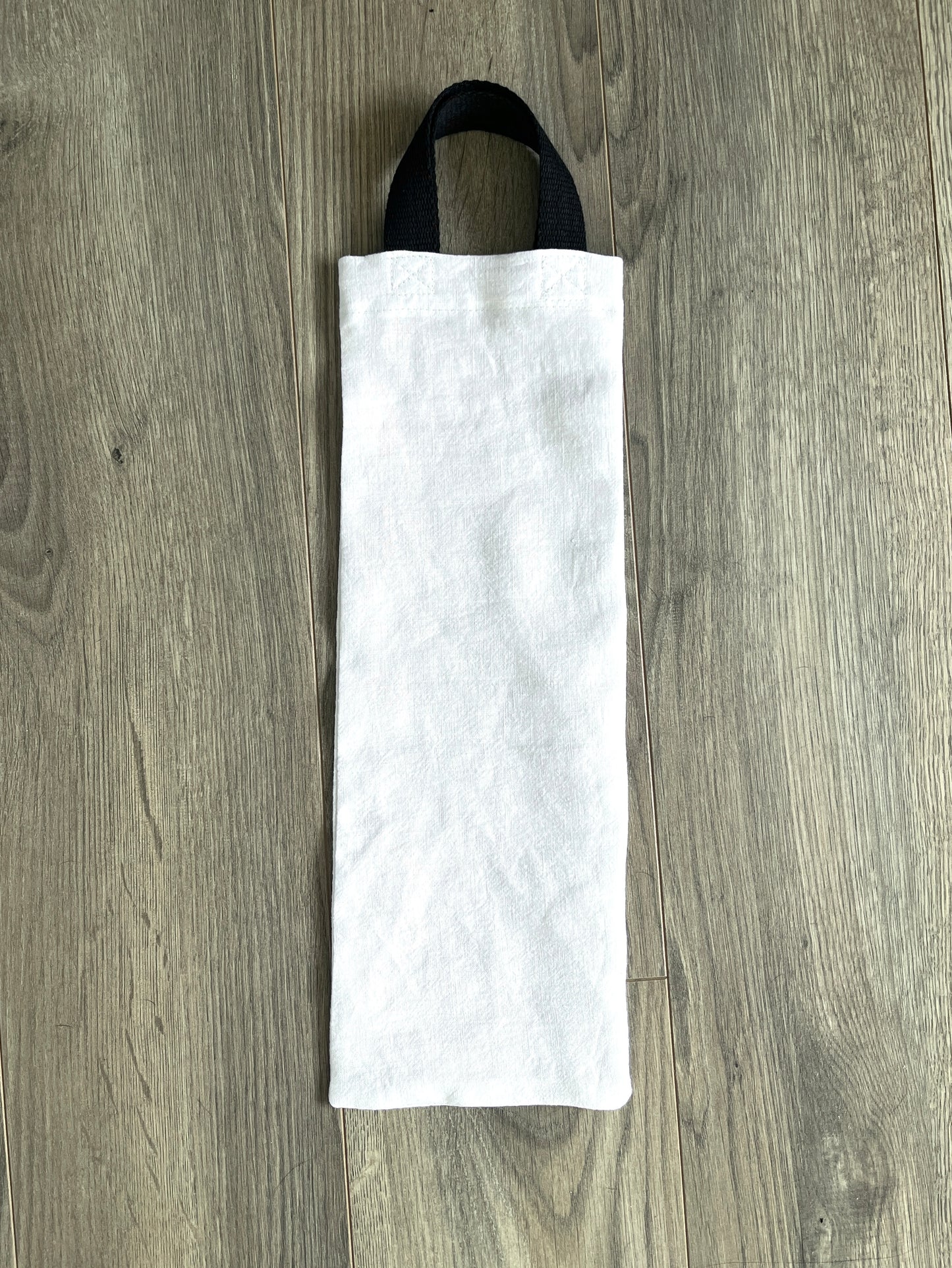 White linen gift bag for bottle, with black cotton strap handles.