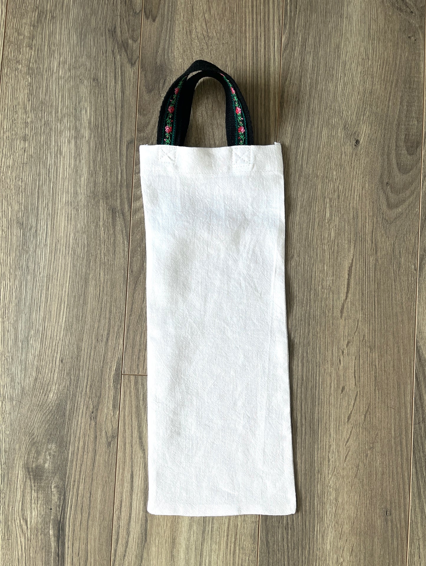 White linen bottle gift bag with floral handles.