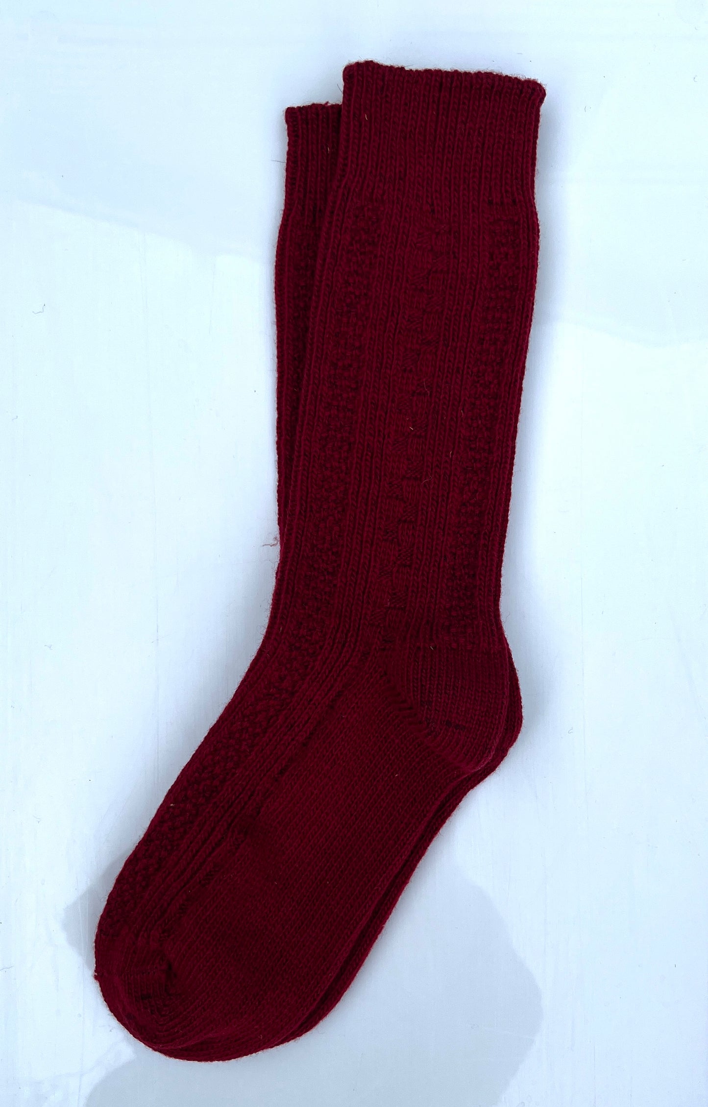 Burgundy color merino wool crew socks, laying flat.